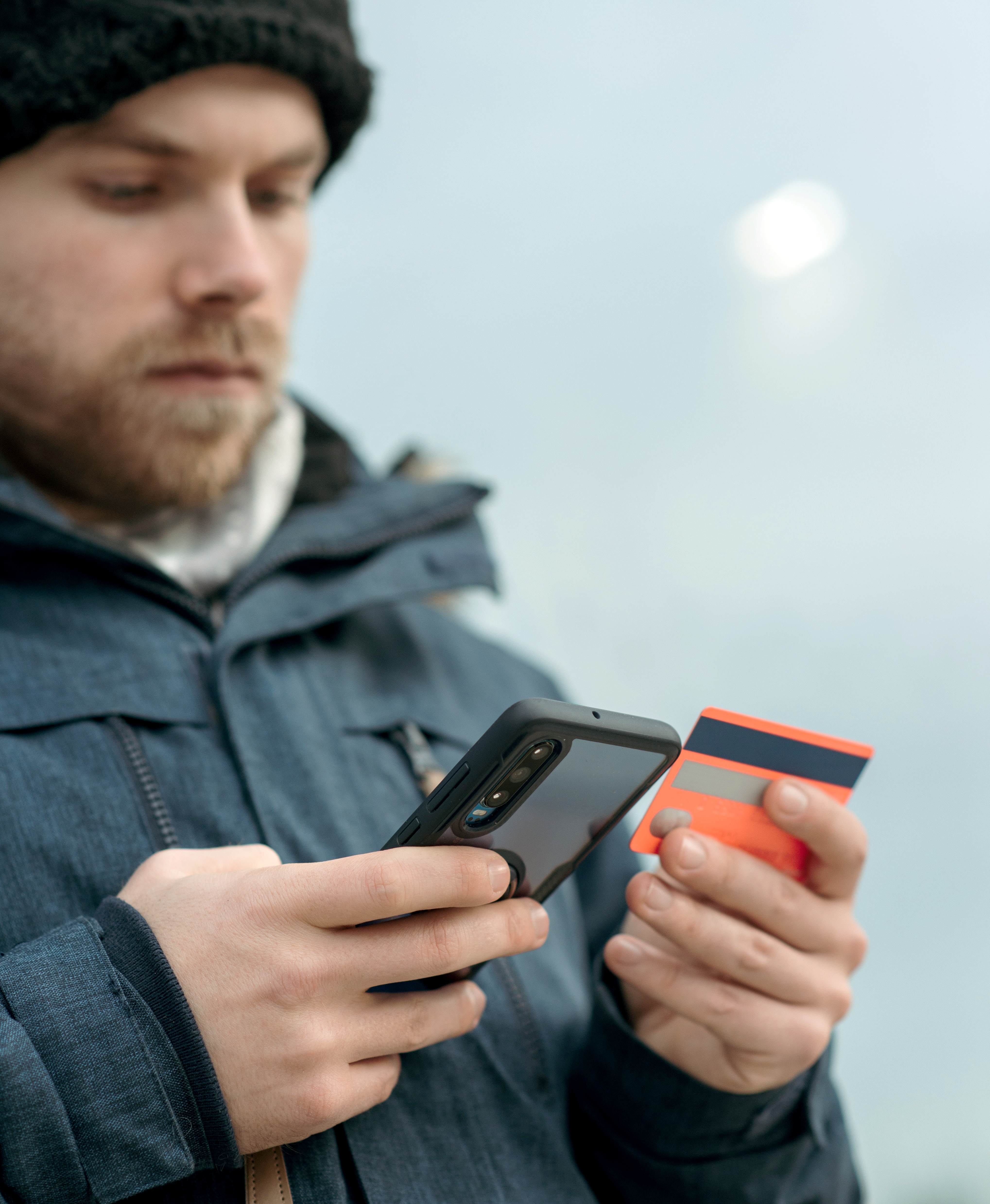 Persona che usa le app su smartphone e tiene in mano una carta bancaria - Abaco Mobility